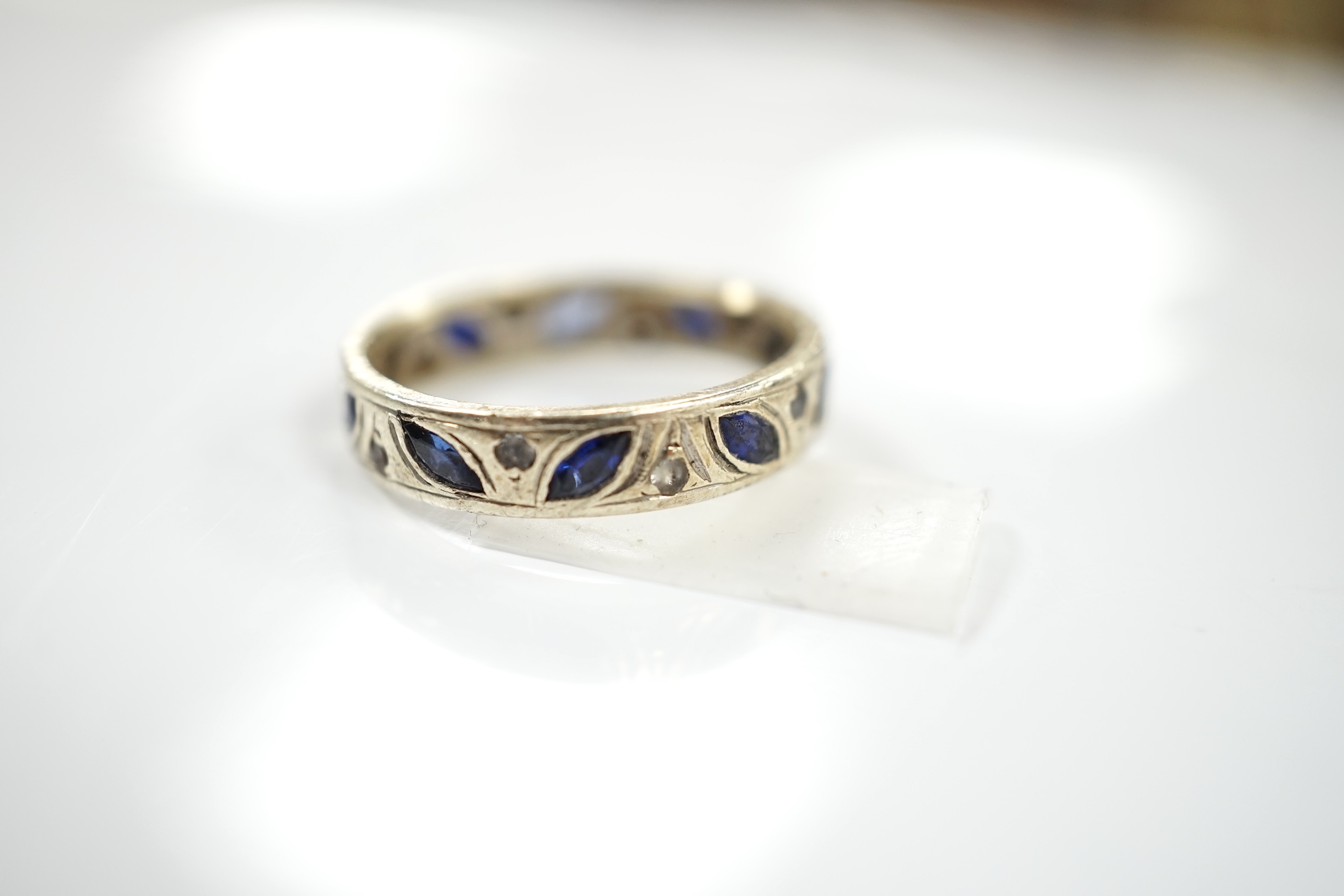 A 9ct white metal, shaped sapphire and diamond chip set eternity ring, size N, gross weight 3.7 grams. Condition - poor